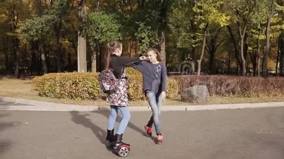 在秋天的公园里两个女朋友骑着电子滑板车视频的预览图