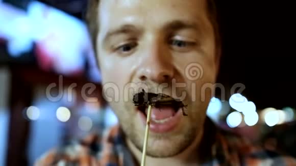在泰国夜市吃蟋蟀的白人年轻男性视频的预览图