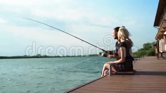 快乐的恋人在阳光下一起旋转甜蜜的一对夫妇坐在码头上拿着棍子视频的预览图