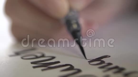 手把字的字母用黑色颜料写在纸上视频的预览图