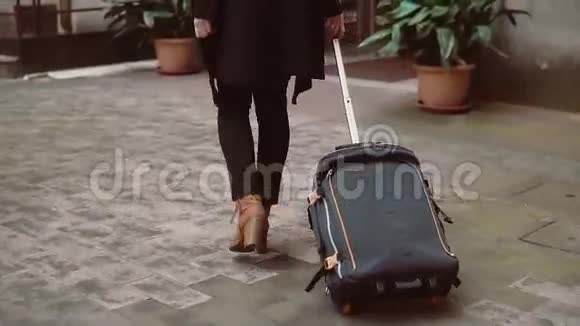 后景的旅客女士腿走路与手提箱在街上女孩走出了城市的入口视频的预览图