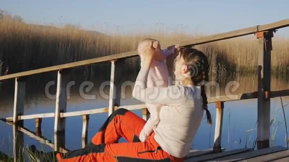 母亲在日落时用手在池塘的岸边养育孩子视频的预览图
