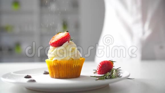 甜点厨师女性手工装饰美味的纸杯蛋糕白色奶油与切好的草莓碎片在厨房视频的预览图