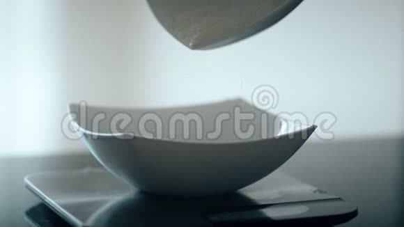 在深深的盘子里站在桌子上在厨房里倒糖面包师把白色粉末涂成陶瓷盘子糖视频的预览图