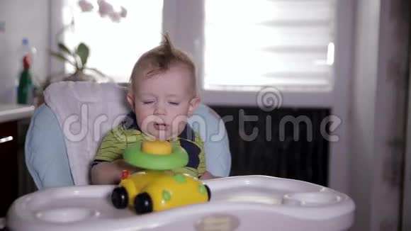 小男孩玩玩具车坐在婴儿椅上一岁的孩子视频的预览图