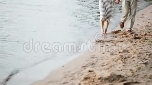 近景男女双脚行走在靠近水面的沙滩上年轻夫妇花时间在大自然上视频的预览图