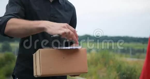 男人手里拿着送货员送的箱子乡野背景的快递员视频的预览图