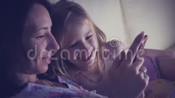 有趣的妈妈和可爱的女儿正在玩平板电脑充满爱意的家庭视频的预览图