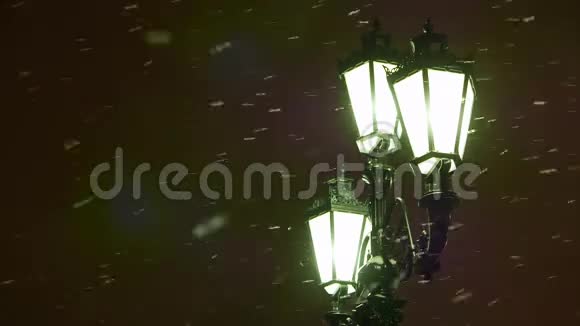 冬天的夜晚雪飞过一盏旧式的路灯分散注意力视频的预览图