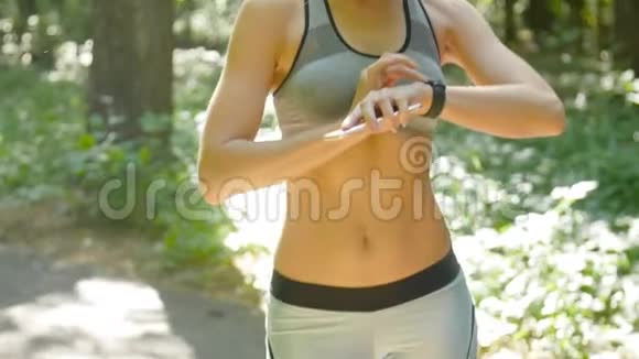 年轻的女运动员在户外练习健身并设置她的有氧运动监视器智能手表视频的预览图