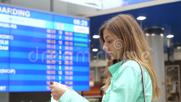 年轻女子看着机场的离境信息委员会视频的预览图