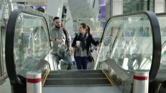 可爱的情侣在机场的自动扶梯上视频的预览图