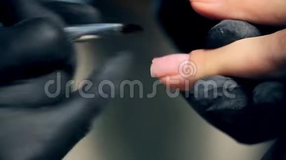 专业的指甲护理过程中化妆师戴着黑色手套做指甲女性客户用多凝胶修指甲视频的预览图