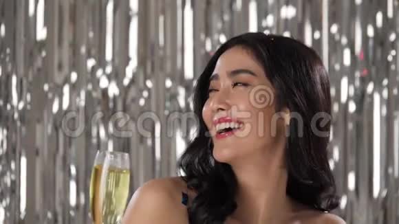美丽的亚洲女人拿着一杯香槟在五彩纸屑中跳舞视频的预览图