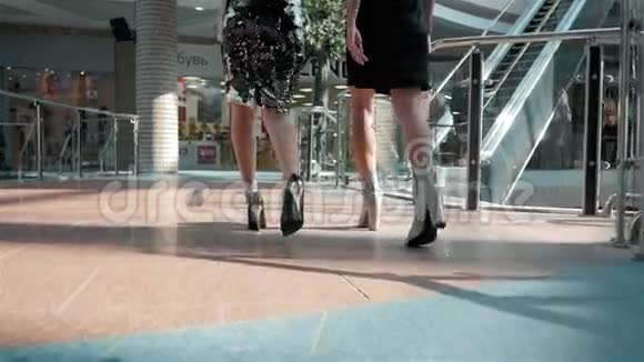 两个女人手里拿着购物袋沿着商店的窗户走着去自动扶梯现代办公室视频的预览图