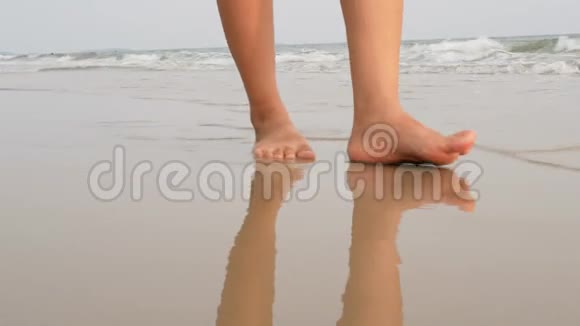 女人的双脚随着海浪在沙滩上行走视频的预览图