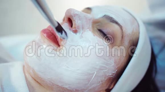 美容师将面膜敷在美容院年轻女性的脸上视频的预览图
