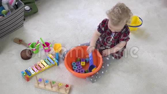 小女孩用大勺子把木砖混在碗里模仿玩具烹饪视频的预览图