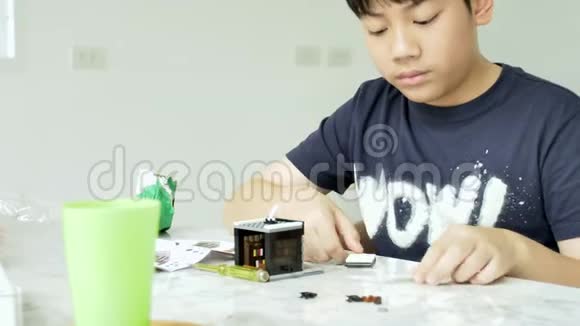 慢动作的亚洲男孩在家里玩塑料块与微笑的脸4K视频的预览图