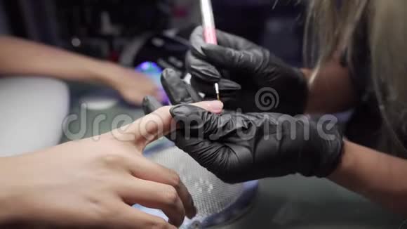 美甲师在美甲沙龙里对女孩的指甲进行修脚和延长指甲的程序视频的预览图