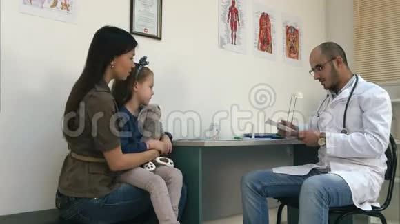 带着小女孩的年轻母亲戴着眼镜看医生视频的预览图