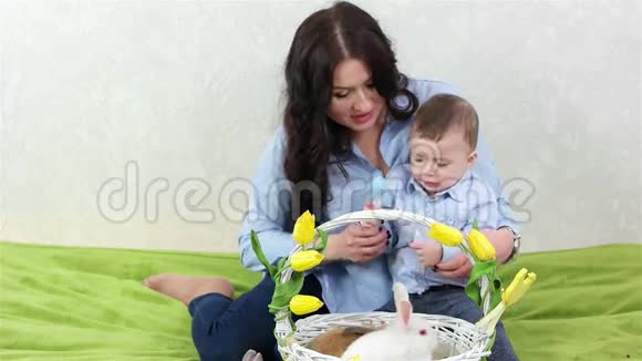 年轻的妈妈和儿子玩耍妈妈和孩子坐在一起孩子玩着五颜六色的鸡蛋视频的预览图