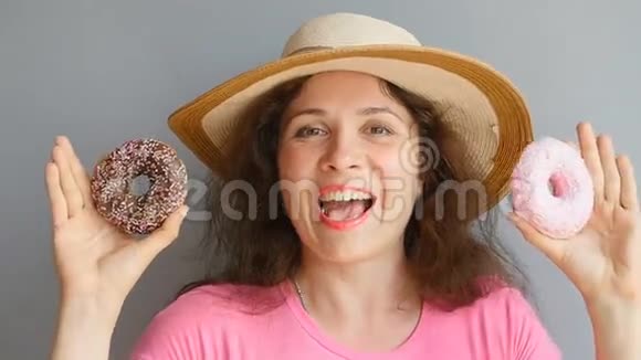 年轻的女人拿着甜甜圈对着她的眼睛微笑着视频的预览图