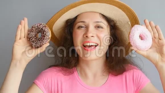 年轻的女人拿着甜甜圈对着她的眼睛微笑着视频的预览图