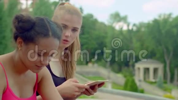 女孩在公园里用ipad学生在公园的平板电脑上联网视频的预览图