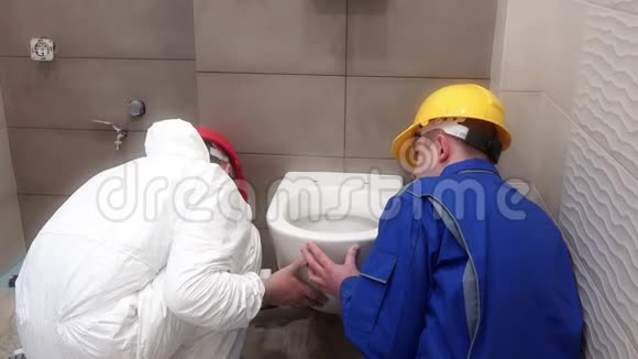 职业工人在新的现代浴室里挂着沉重的马桶视频的预览图