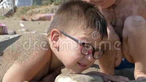 小男孩被埋在海边的沙滩上视频的预览图