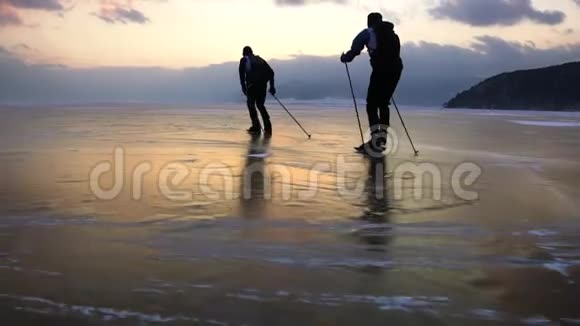 在美丽的日落中两个人正在冰封的贝加尔湖上滑冰视频的预览图