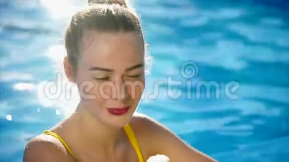 一个穿着泳衣的年轻女人在游泳池里喝着喇叭里的冰淇淋视频的预览图