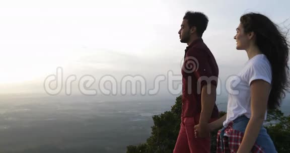 两个人在山顶牵手拉丁男人向女人展示晨景点指视频的预览图