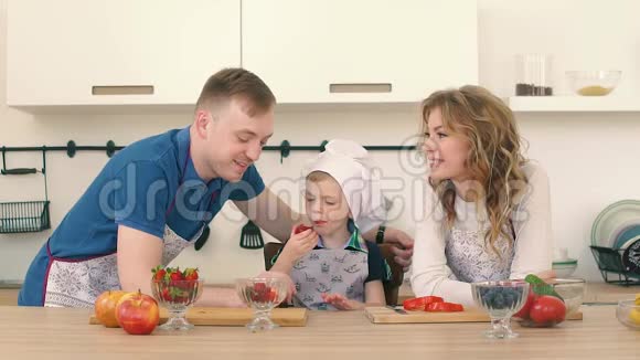 父母在厨房里用草莓喂儿子他们正在准备早餐视频的预览图