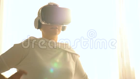 漂亮的年轻女性戴着虚拟现实眼镜玩游戏视频的预览图