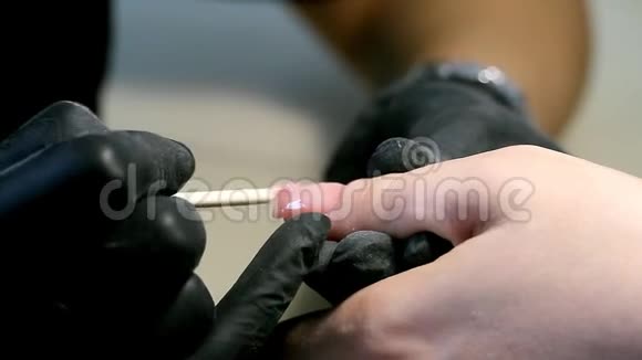 专业的指甲护理过程中化妆师戴着黑色手套做指甲女性客户用多凝胶修指甲视频的预览图