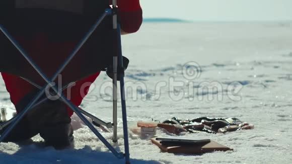 钓鱼的人在冬湖钓鱼把成功的鱼放在冰上视频的预览图