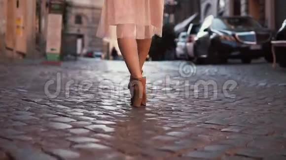 女人走在鹅卵石路面上女孩穿着鞋子和裙子探索新城市特写镜头视频的预览图