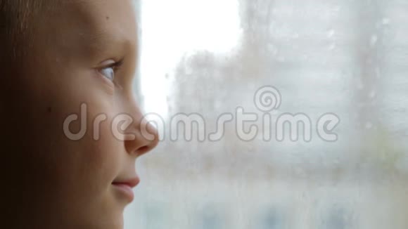 伤心的男孩在雨天看窗外视频的预览图