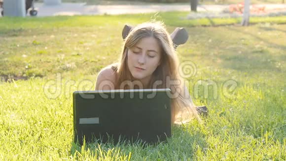 在外面草地上的笔记本电脑上的女人视频的预览图