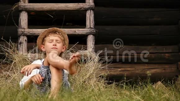 光脚男孩睡在干草堆梯子附近的草地上视频的预览图