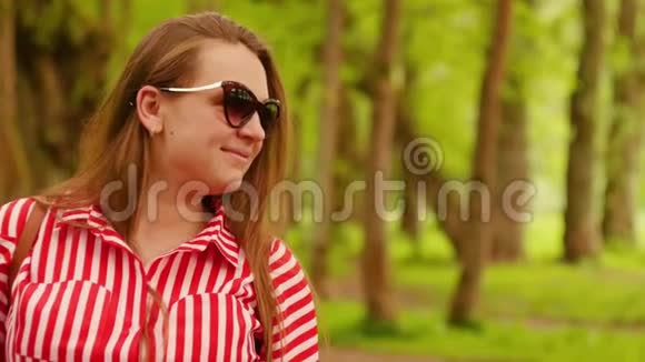 夏天穿红色衣服的年轻女人的肖像幸福的年轻女子对着镜头微笑视频的预览图