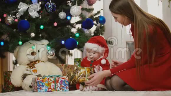 妈妈带着婴儿穿着圣诞服装看礼物视频的预览图