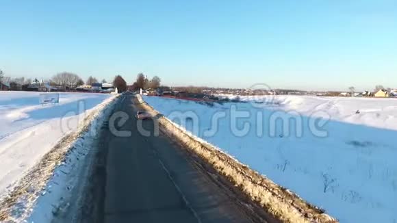 在金色日出的时候在一条雪道上在汽车上方飞行在寒冷的道路上行驶的汽车视频的预览图