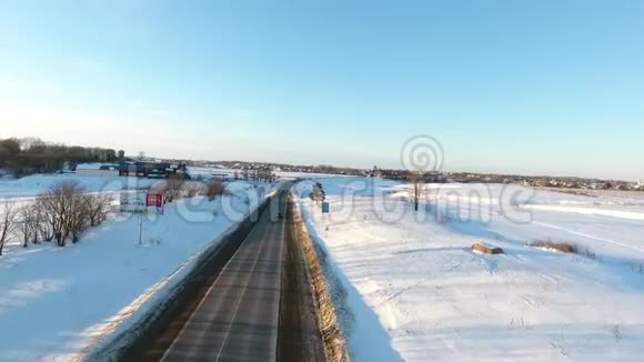 在金色日出的时候在一条雪道上在汽车上方飞行在寒冷的道路上行驶的汽车视频的预览图