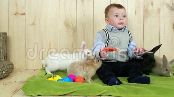 孩子坐在绿色的地板上孩子和可爱的兔子玩五颜六色的复活节彩蛋视频的预览图
