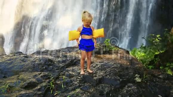 小金发女郎站在石头上对抗大瀑布视频的预览图