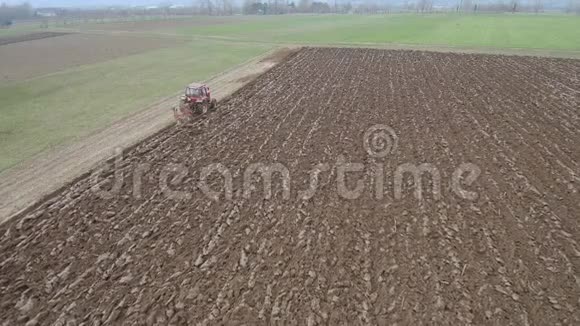 农业和农业拖拉机在早春的空中镜头下犁田视频的预览图