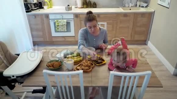 家庭食物孩子营养和亲子观念快乐的年轻母亲和婴儿一起吃早餐视频的预览图